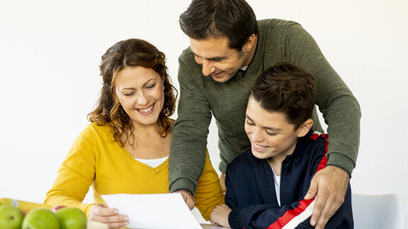 Eltern und Kind freuen sich über gute Schulnoten